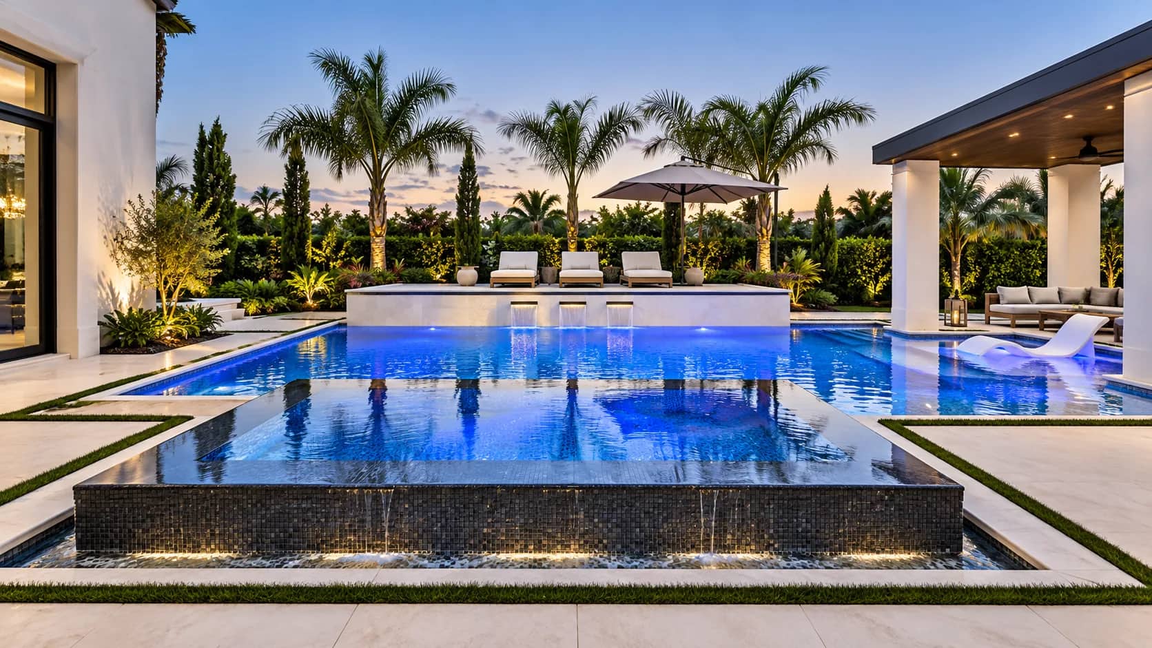 Modern Florida pool with a raised infinity-edge spa and lighting at dusk